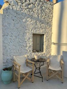 a table and two chairs next to a stone wall at Mikro Kastro in Amorgos
