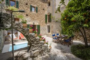 a courtyard with a table and chairs and an orange tree at Ca Sa Padrina in Artá