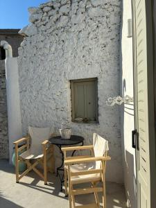 a patio with a table and chairs and a wall at Mikro Kastro in Amorgos +10 photos