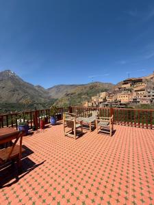 a patio with benches and mountains in the background at Jnane Karma in Imlil