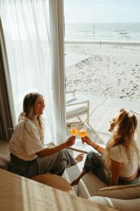 two women sitting at a table with glasses of wine at Lua Beach House in Zandvoort +9 photos