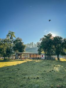 a field with a building and trees in the background at Camping Rio do Rastro in Lauro Müller