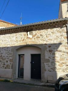 a stone building with a black door on it at L'Amandine in Puisserguier