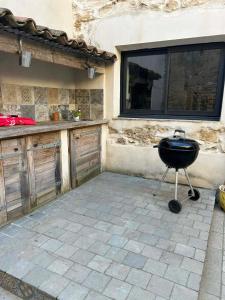 a barbecue grill in a patio with a building at L'Amandine in Puisserguier
