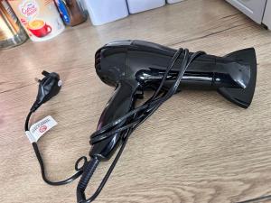a black hair dryer sitting on a wooden floor at Park Street Accommodation, Room 2 in Luton