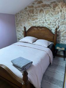a bedroom with a large bed with a stone wall at L'Amandine in Puisserguier
