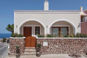 a house with a stone wall and a gate at Centro Houses in Fira