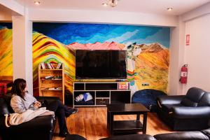 a woman sitting in a living room with a mural at Magic Packer Hostel in Cusco +70 photos