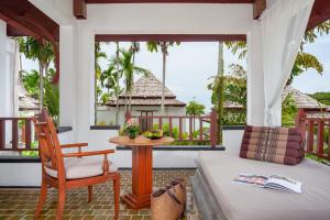 a room with a bed and a table on a porch at Nakamanda Resort and Spa in Klong Muang Beach