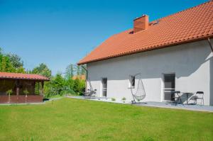 a white house with a yard with chairs and a roof at Apartamenty Suchacz in Suchacz