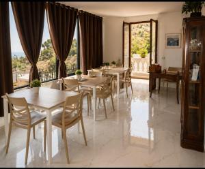a dining room with tables and chairs and large windows at INCANTO Golden Place B&B in Reggio di Calabria
