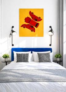 a bed with a blue headboard and a painting of red cars at Botanique Rooms with Sauna by Homester in Brno