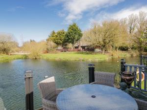 a table and chairs on a porch with a view of a lake at Carp Lodge in Carnforth