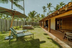 a patio with a bench and an umbrella next to a house at Reserva Jacumã Boutique Hotel in Trancoso