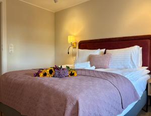 a bed with a purple comforter and flowers on it at ToRUŃ ApartHotel z widokiem na Wisłę i Krzywą Wieżę in Toruń