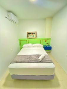 a bedroom with a large bed with a green headboard at Hostal Marle in Portoviejo
