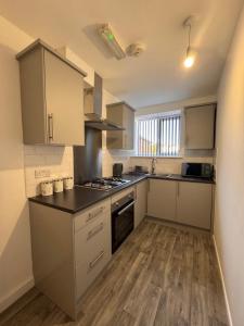 a kitchen with white cabinets and a wooden floor at Serenity LTD in Leicester