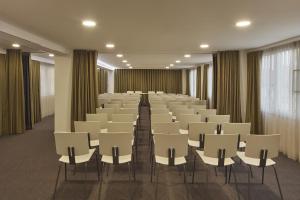 an empty room with white chairs and curtains at Grace Smart Design Hotel - "Hotel Anjo de Portugal" in Fátima