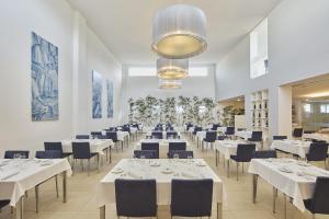 a dining room with white tables and blue chairs at Grace Smart Design Hotel - "Hotel Anjo de Portugal" in Fátima