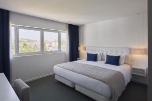 a hotel room with a large bed with blue pillows at Grace Smart Design Hotel - "Hotel Anjo de Portugal" in Fátima +26 photos
