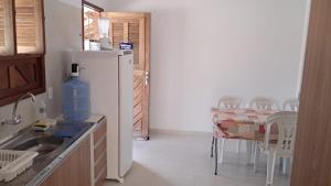 a kitchen with a refrigerator and a table with chairs at Paraíso dos Falcões in Nísia Floresta