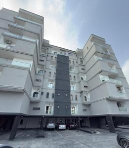a large building with cars parked in a parking lot at Premium 2 Bedroom Maisonette with Ps5 & Pool in Lekki