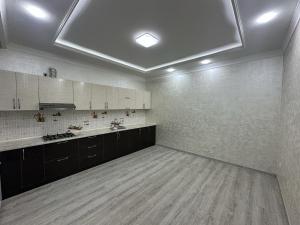 a large kitchen with white walls and wooden floors at Art Angren Hotel in (( Sotsgorod ))