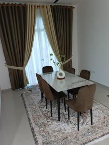 a dining room with a table and chairs on a rug at SD Homestay in Bachok
