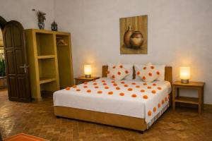 a bedroom with a large bed with orange pillows at Riad les trois merveilles in Essaouira