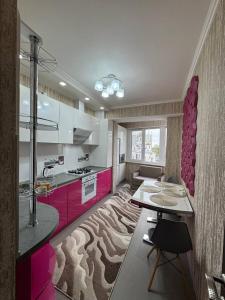 eine Küche mit rosa und weißen Schränken und einem Tisch in der Unterkunft Flora in Chişinău