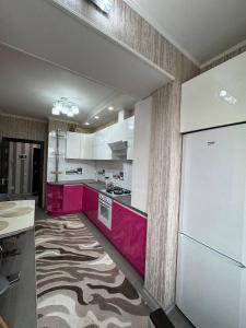 eine Küche mit rosa und weißen Schränken und einem Teppich in der Unterkunft Flora in Chişinău