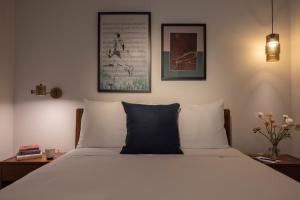 a bedroom with a bed with white sheets and two pictures at The Promissory Hotel in Roanoke