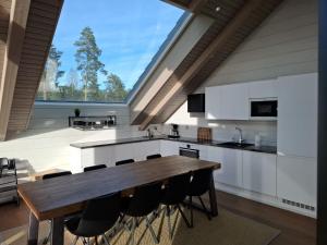a kitchen with a wooden table and a large window at Naava Chalet 401 Penthouse - Järvinäköala ilta-aurinkoon in Ähtäri