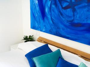 a white bed with blue pillows and a painting at Orizzonte Blu - HelloElba in Marciana Marina