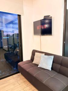 a brown couch in a room with a television at Eon 2 - Apartamento en edificio con piscina in Estación Pamplona