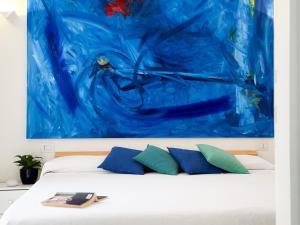 a bed with two pillows and a blue painting at Orizzonte Blu - HelloElba in Marciana Marina