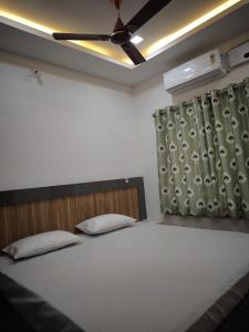 a bedroom with a large white bed with a ceiling at Anand palace lodge in Ghatgān +1 photo