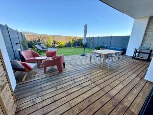 a wooden deck with a table and chairs on it at À Casetta Porticcio Spacieux T2 50m2 Neuf Terrasse & Jardin privatif à 3min des plus belles plages in Porticcio +53 photos