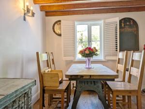 a dining room with a table with a vase of flowers on it at Springwell , West Wittering in West Wittering +12 photos