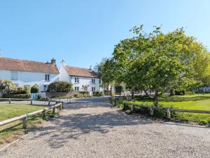 a road in a village with houses and a tree at Springwell , West Wittering in West Wittering