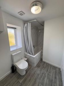 a white bathroom with a toilet and a bath tub at Serenity LTD in Leicester