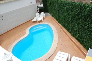 a swimming pool with white chairs and a hedge at Lancelot in Puerto Rico de Gran Canaria