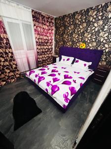 a bedroom with a purple bed with pink flowers on it at Apartament CC in Drobeta-Turnu Severin +2 photos