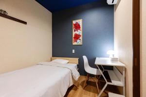 a bedroom with a bed and a desk and a table at Guest House BLUE DOOR in Imabari Railway Station +18 photos