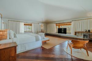 a large bedroom with a white bed and a television at Reserva Jacumã Boutique Hotel in Trancoso