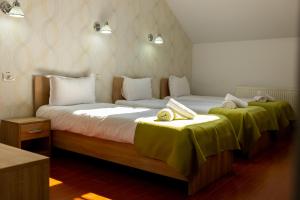 two beds in a hotel room with green sheets at MARCONI GUESTHOUSE in Hunedoara
