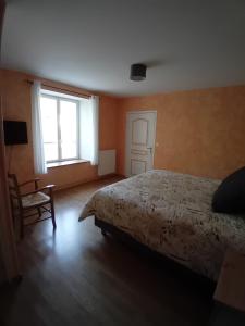 a bedroom with a bed and a chair and a window at Les Castelblotines in Châteaubleau
