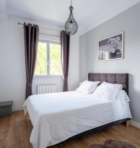 a bedroom with a bed with white sheets and a window at appartement 15min de Paris in Drancy
