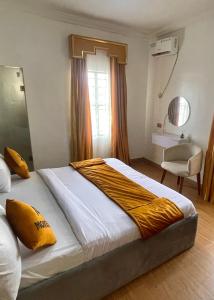 a bedroom with a large bed with a yellow blanket on it at Montevar Hotel in Benin City