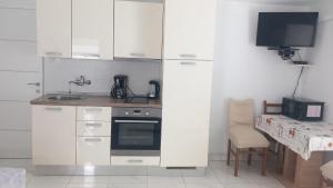 a kitchen with white cabinets and a table with a television at Danica Karlobag in Karlobag